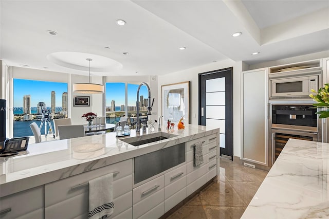 kitchen featuring light stone counters, white cabinetry, hanging light fixtures, and white microwave