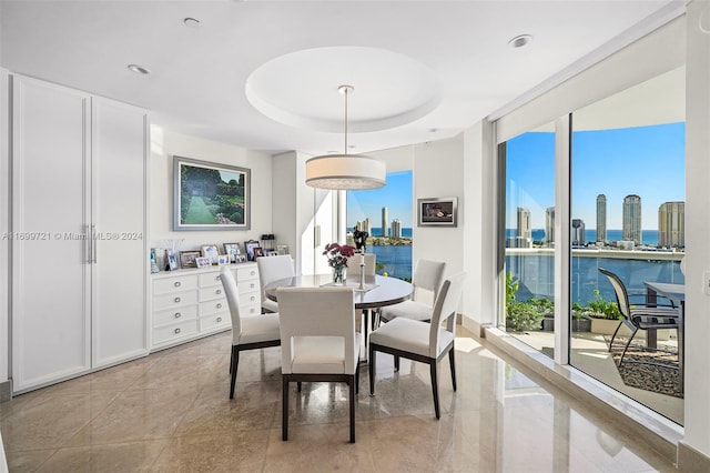 dining area with a tray ceiling and a water view