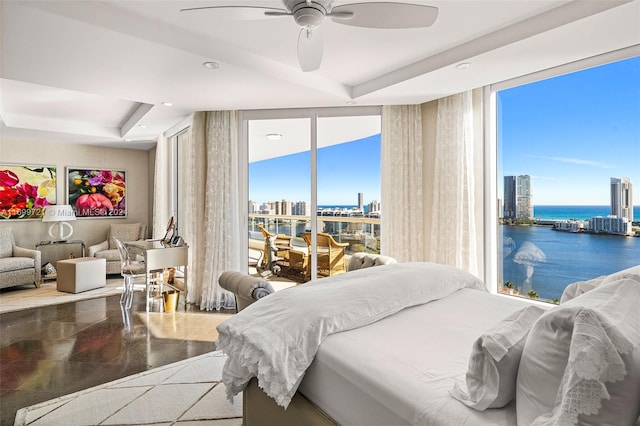 bedroom featuring ceiling fan, a water view, and a tray ceiling