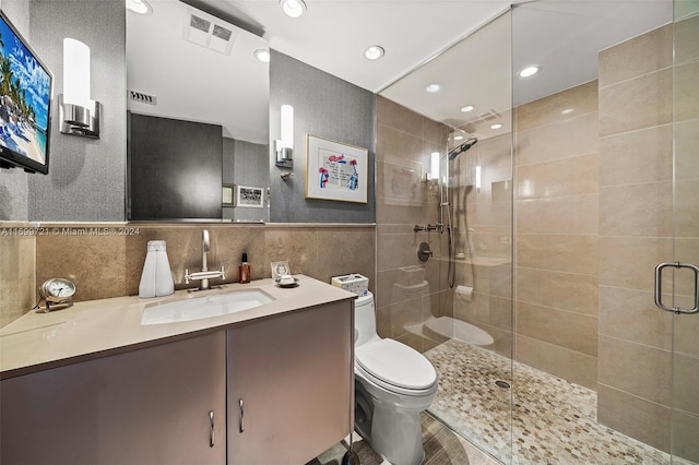 bathroom featuring an enclosed shower, vanity, toilet, and tile walls