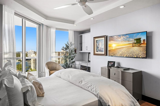 bedroom with ceiling fan, a raised ceiling, and wood-type flooring