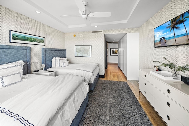 bedroom with a raised ceiling, ceiling fan, and dark hardwood / wood-style flooring