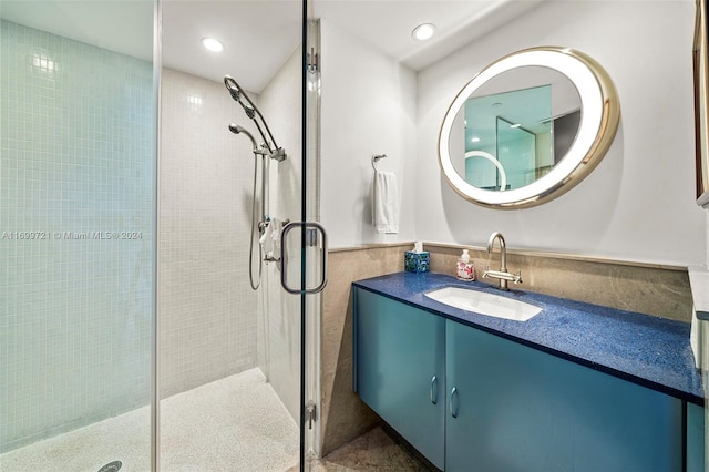 bathroom with vanity, an enclosed shower, and tile walls