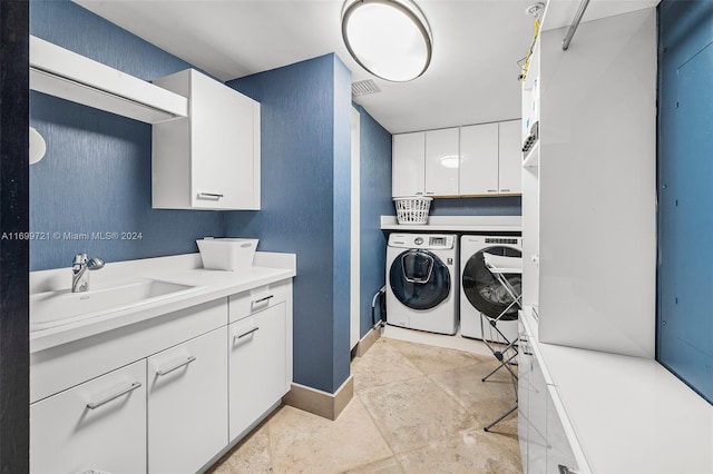 washroom with cabinets, washer and clothes dryer, and sink