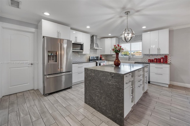 kitchen with white cabinets, wall chimney exhaust hood, a kitchen island, and stainless steel appliances