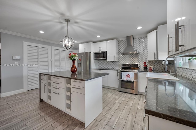 kitchen featuring white cabinetry, wall chimney range hood, pendant lighting, a kitchen island, and appliances with stainless steel finishes