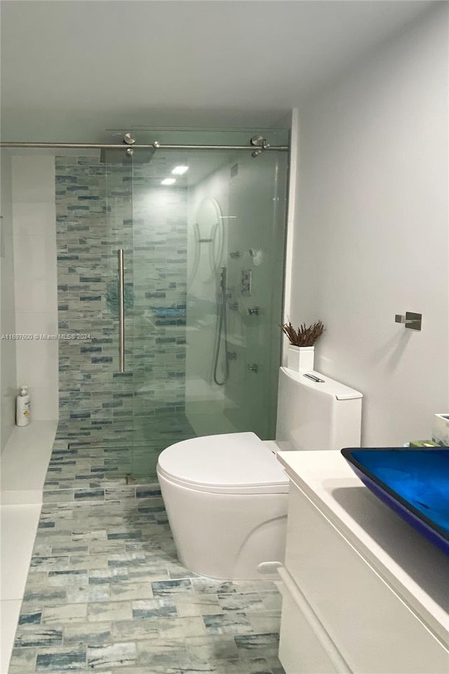 bathroom with tiled shower, vanity, and toilet