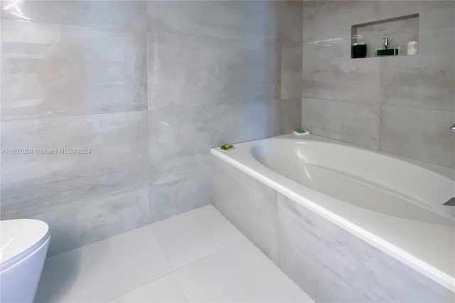 bathroom featuring tile patterned flooring, toilet, tile walls, and tiled tub