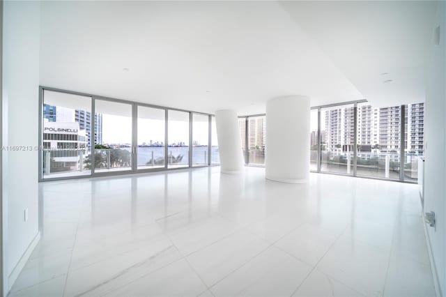 spare room featuring expansive windows and light tile patterned flooring