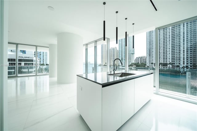 kitchen featuring pendant lighting, a healthy amount of sunlight, white cabinetry, and sink