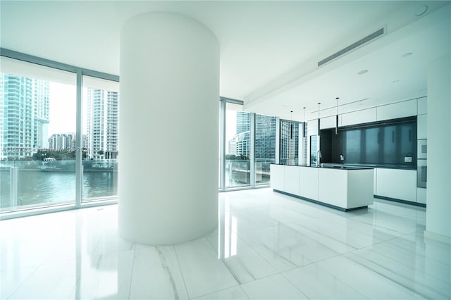 interior space featuring white cabinets, decorative light fixtures, expansive windows, and a healthy amount of sunlight