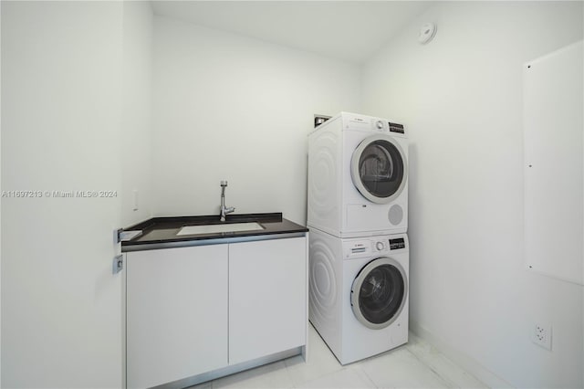 laundry area featuring sink, cabinets, and stacked washer and clothes dryer