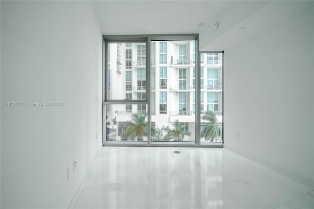 tiled spare room with a wall of windows