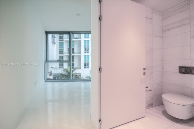 bathroom featuring tile patterned flooring, toilet, and tile walls