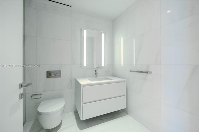 bathroom featuring vanity, tile walls, and toilet