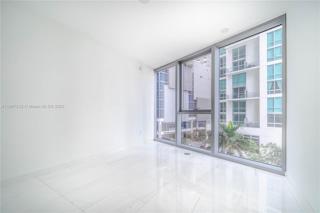 unfurnished room featuring floor to ceiling windows and light tile patterned flooring