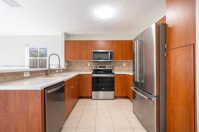 kitchen featuring sink, stainless steel appliances, kitchen peninsula, decorative backsplash, and light tile patterned floors