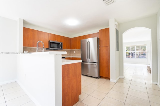 kitchen featuring backsplash, sink, light tile patterned floors, kitchen peninsula, and stainless steel appliances