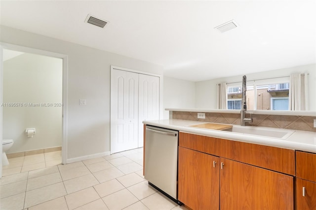 kitchen featuring light tile patterned flooring, tasteful backsplash, stainless steel dishwasher, and sink