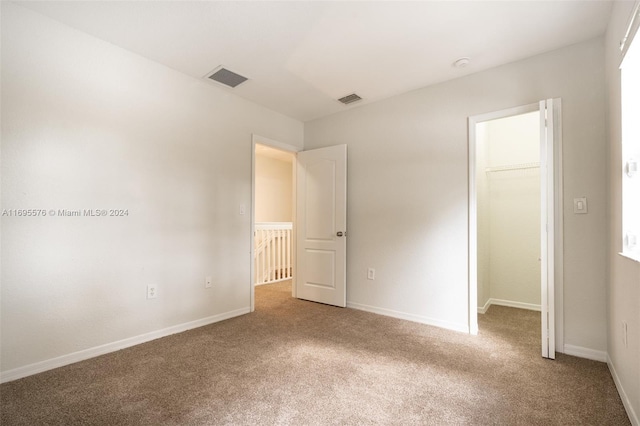 unfurnished bedroom with carpet flooring, a walk in closet, and a closet