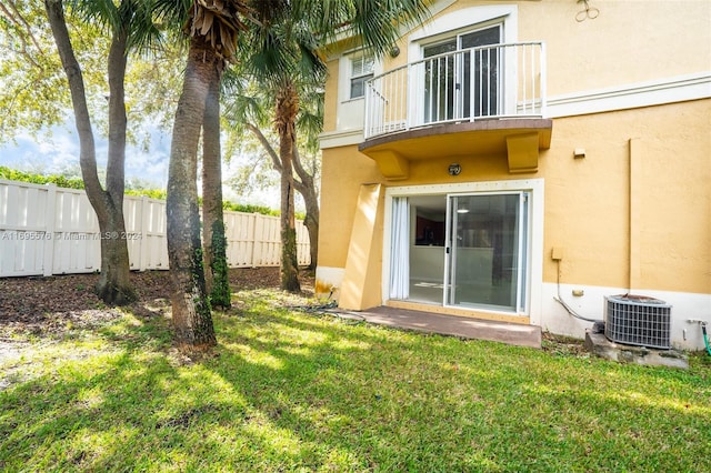 back of house featuring a lawn, a balcony, and central AC unit