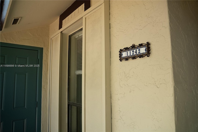 exterior details featuring stucco siding and visible vents