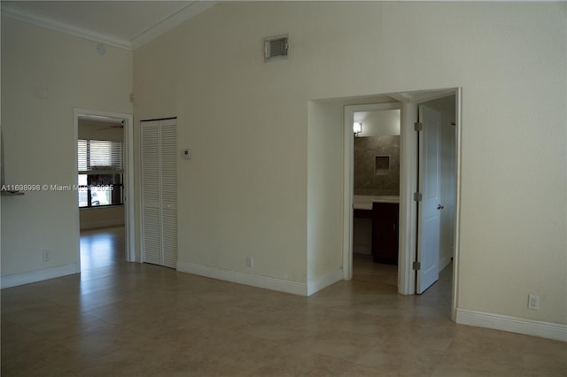 spare room with visible vents, a towering ceiling, baseboards, and ornamental molding