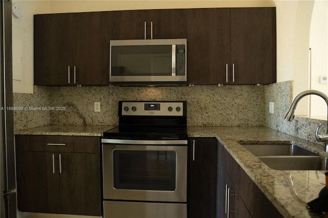 kitchen featuring a sink, dark brown cabinetry, tasteful backsplash, and stainless steel appliances