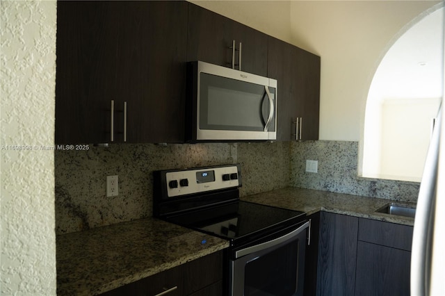 kitchen with backsplash, stainless steel appliances, and light stone countertops