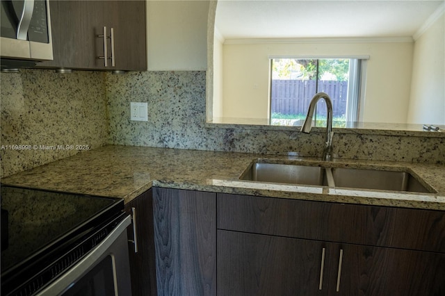 kitchen featuring stainless steel microwave, crown molding, decorative backsplash, and a sink