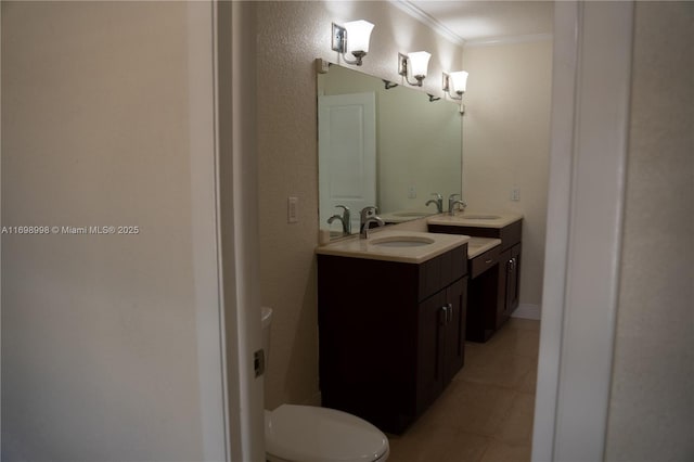 bathroom featuring a sink, toilet, ornamental molding, and double vanity