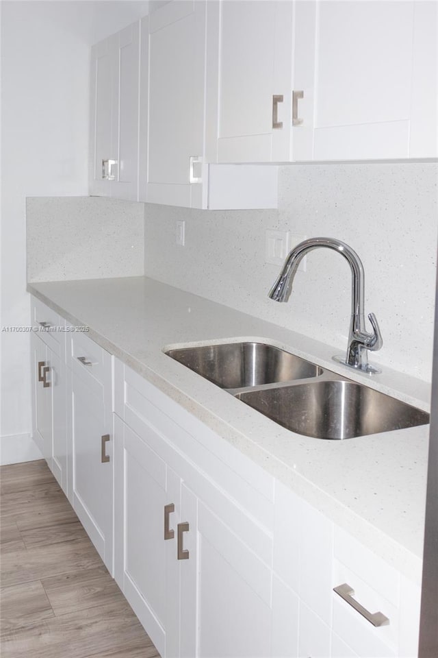 kitchen featuring light stone countertops, white cabinetry, tasteful backsplash, and sink