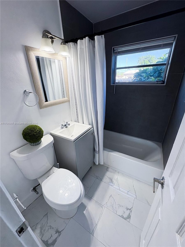 bathroom featuring toilet, marble finish floor, shower / bath combo with shower curtain, and vanity