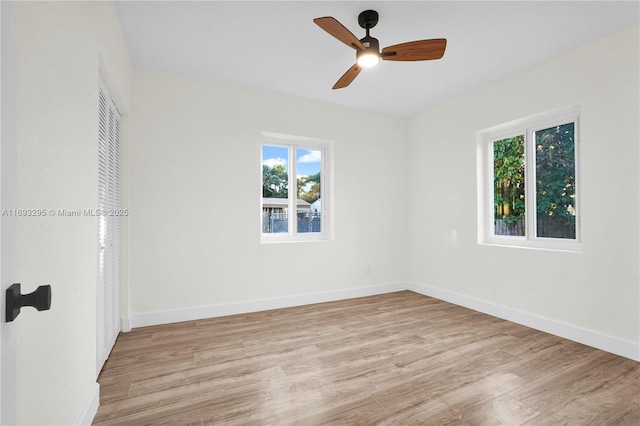 spare room featuring baseboards, wood finished floors, and a ceiling fan