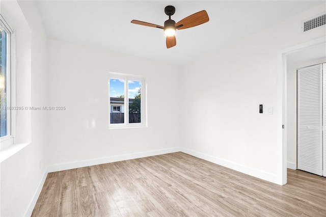 spare room featuring a ceiling fan, light wood-style flooring, baseboards, and visible vents