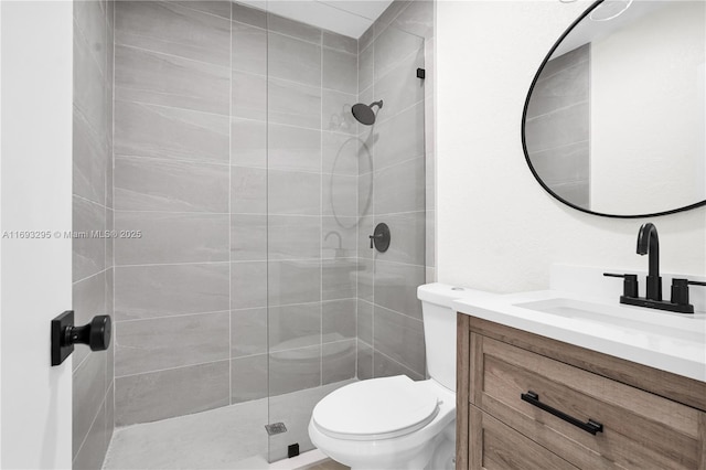 full bathroom with a tile shower, toilet, and vanity