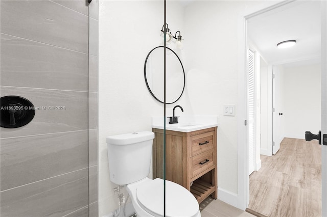 bathroom featuring baseboards, wood finished floors, toilet, and vanity
