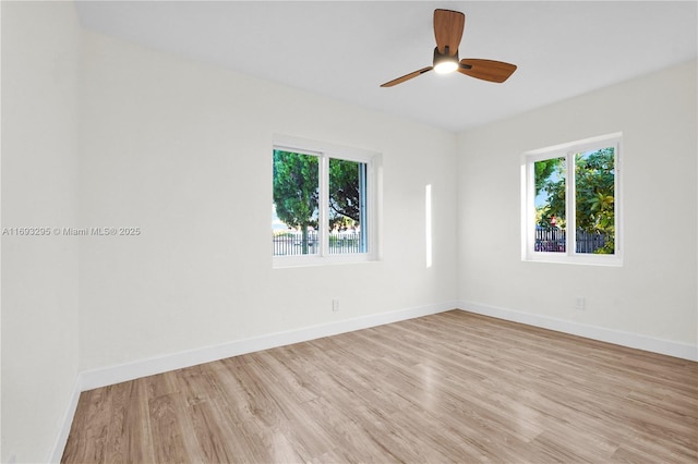 unfurnished room with baseboards, a wealth of natural light, light wood-style flooring, and ceiling fan