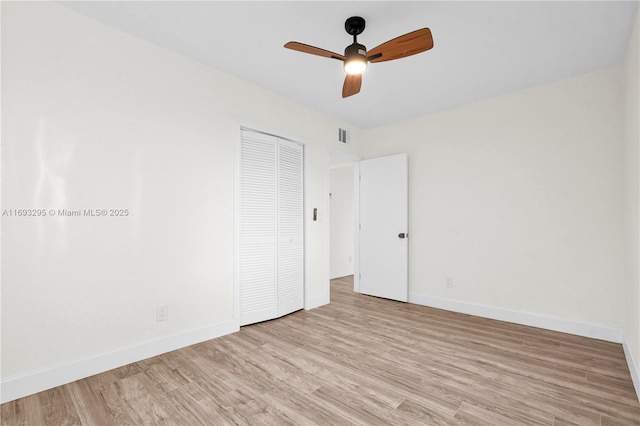 unfurnished room featuring baseboards, visible vents, light wood-style floors, and ceiling fan