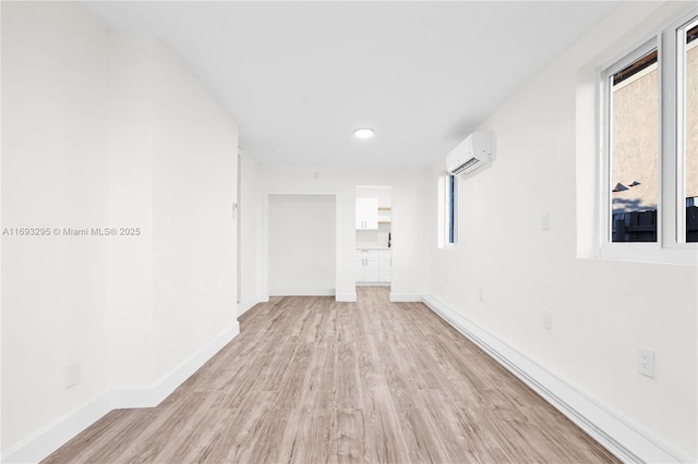 unfurnished room featuring a wall mounted air conditioner and light hardwood / wood-style floors