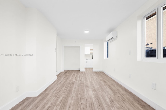 unfurnished room featuring a wall unit AC, a wealth of natural light, and light hardwood / wood-style floors