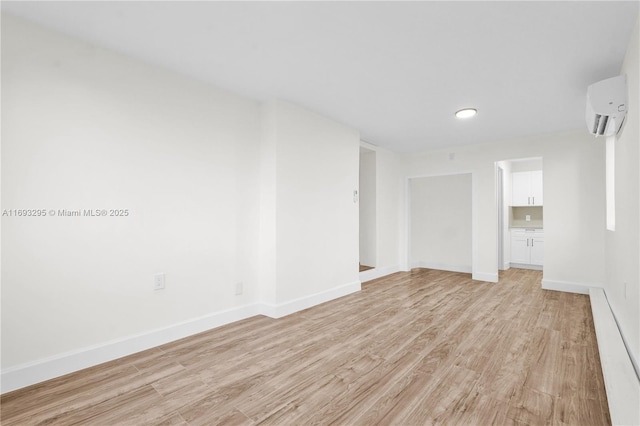 unfurnished room featuring light wood-type flooring and a wall unit AC