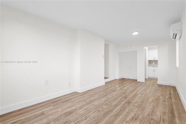 empty room with light hardwood / wood-style floors and a wall unit AC