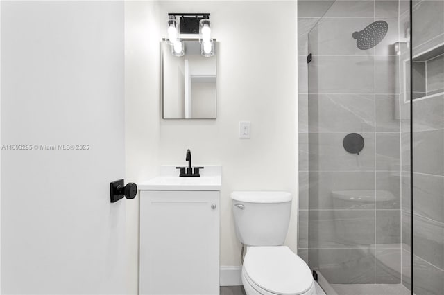 bathroom with vanity, toilet, and tiled shower