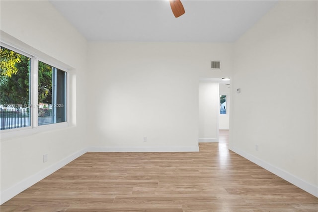 empty room with a ceiling fan, baseboards, light wood-style flooring, and visible vents