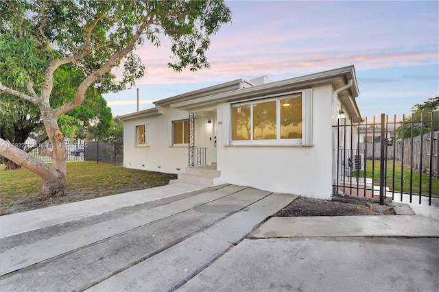 view of front facade featuring a front lawn, stucco siding, and fence