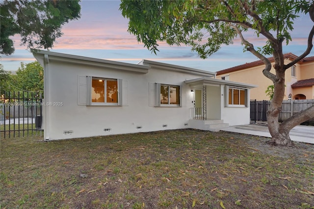 view of front of property with stucco siding, fence, a front lawn, and crawl space