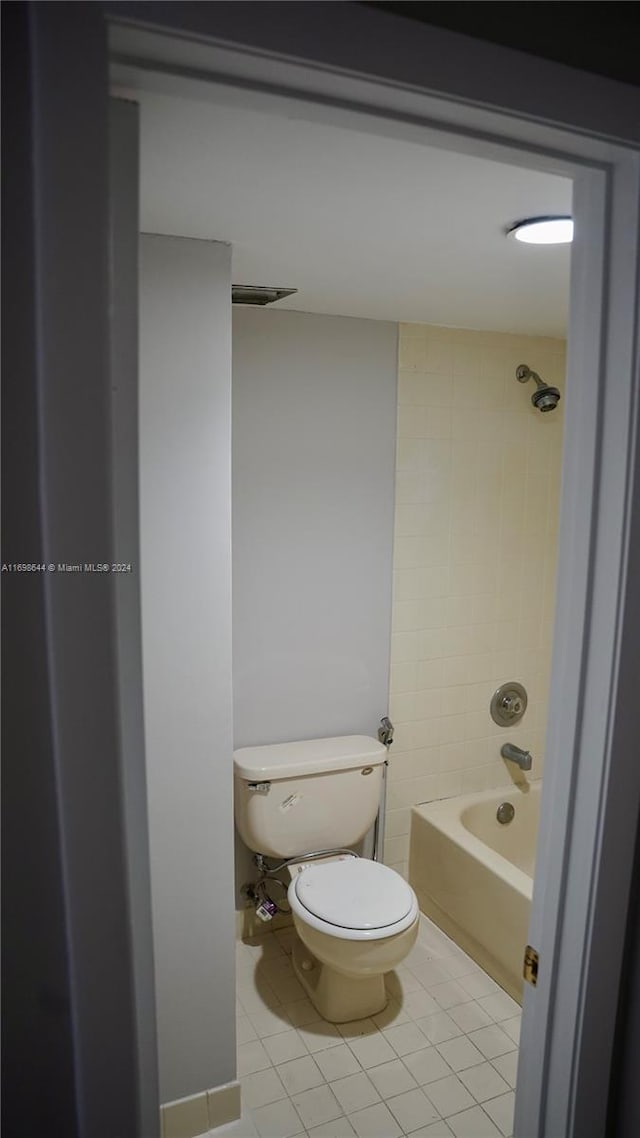 bathroom with tile patterned floors, tiled shower / bath combo, and toilet