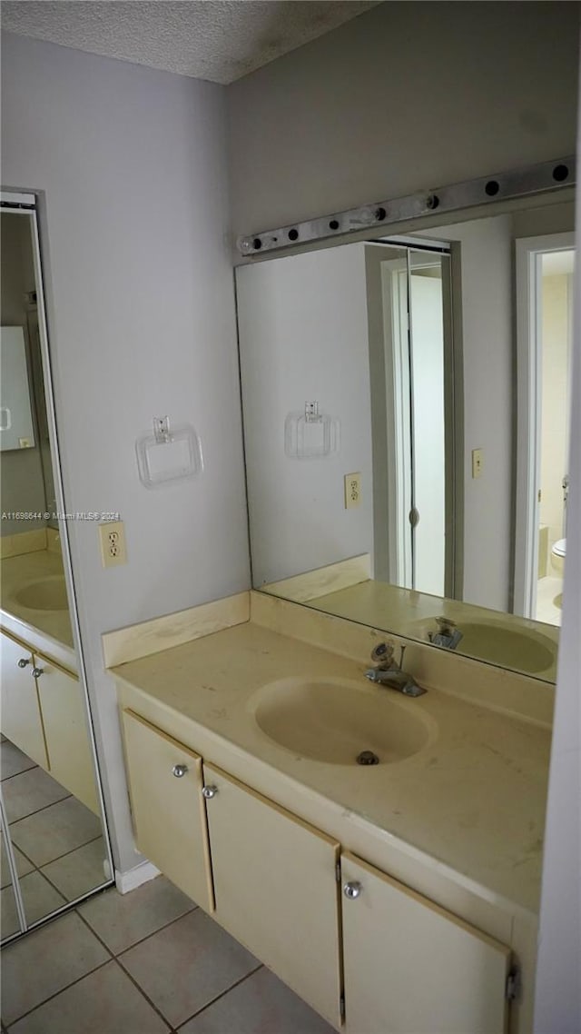 bathroom with vanity, a textured ceiling, and tile patterned floors