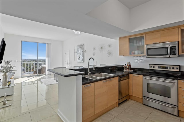 kitchen with sink, kitchen peninsula, dark stone counters, light tile patterned floors, and appliances with stainless steel finishes